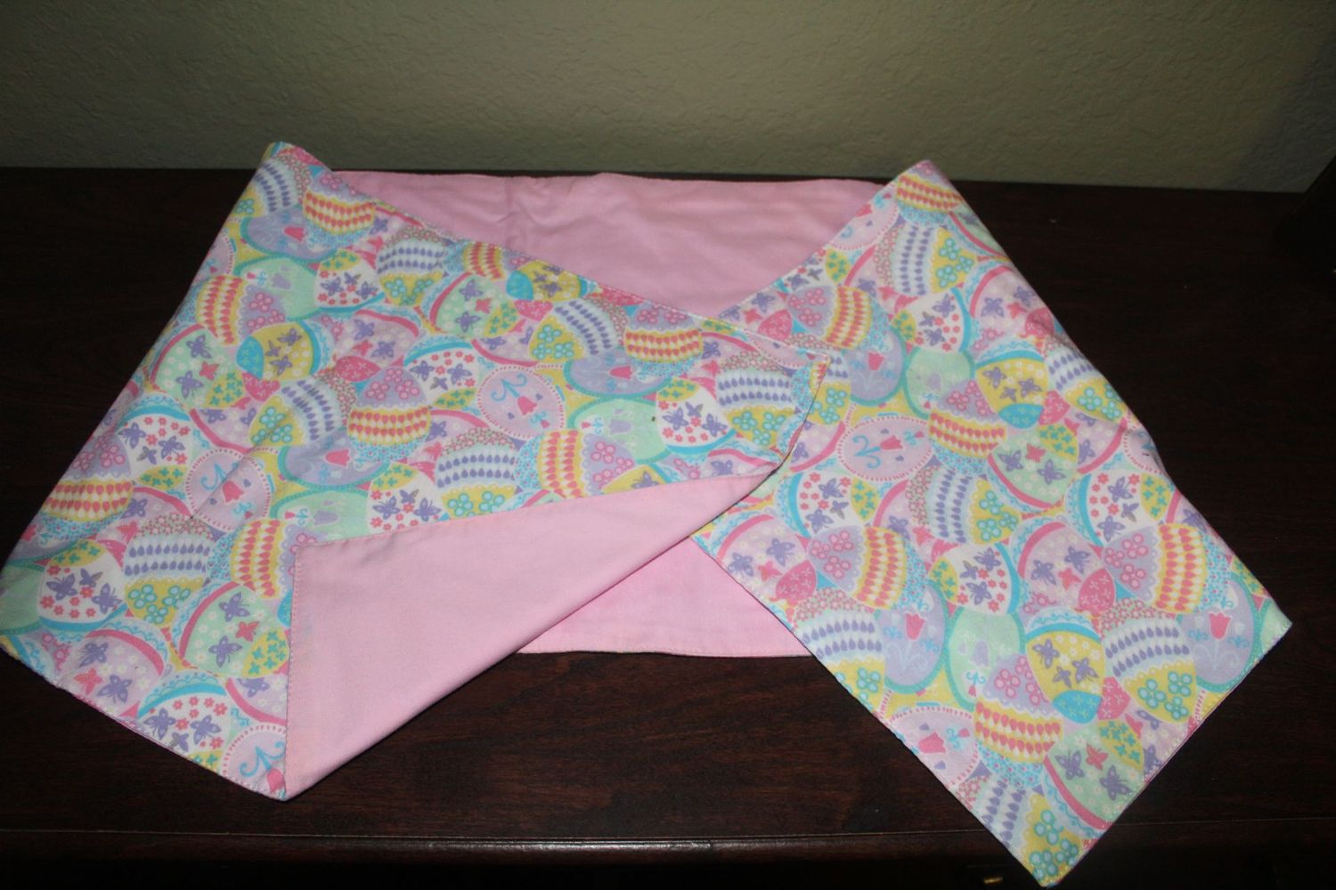 Handmade reversible Easter table runner with pastel egg pattern and pink backing.