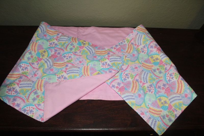 Handmade reversible Easter table runner with pastel egg pattern and pink backing.