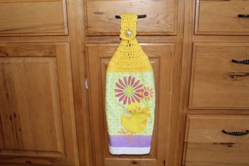 Easter chick kitchen towel with yellow crochet top and spring flower pattern hanging on cabinet handle.
