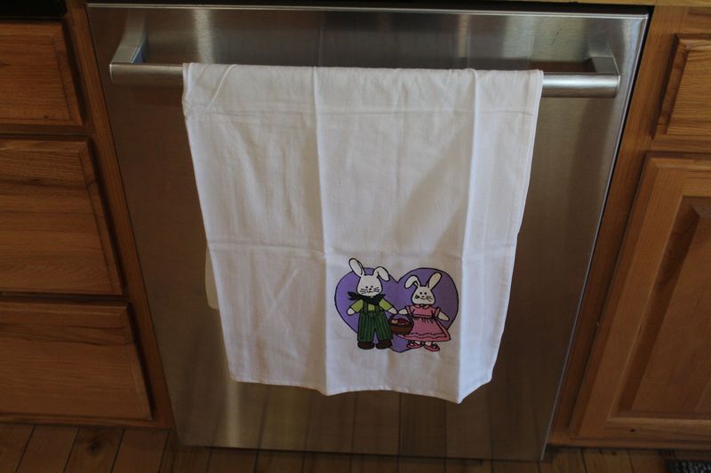 Hand painted Easter bunny couple kitchen towel with rabbits holding basket and purple heart background.