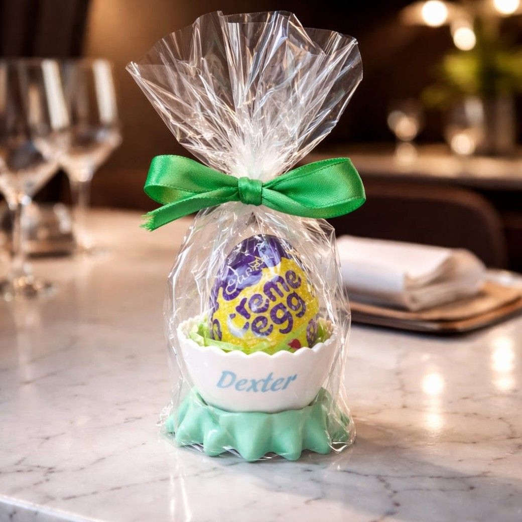 Personalised Easter egg cup shaped like a cracked egg, filled with tissue, a Creme Egg, and a vinyl name.”