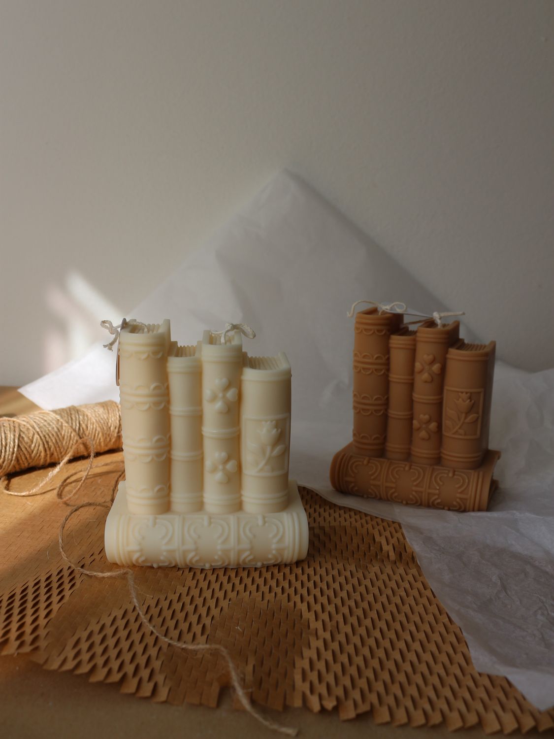 Coppia di candele decorative a forma di pila di libri nelle colorazioni disponibili di bianco e caffelatte
