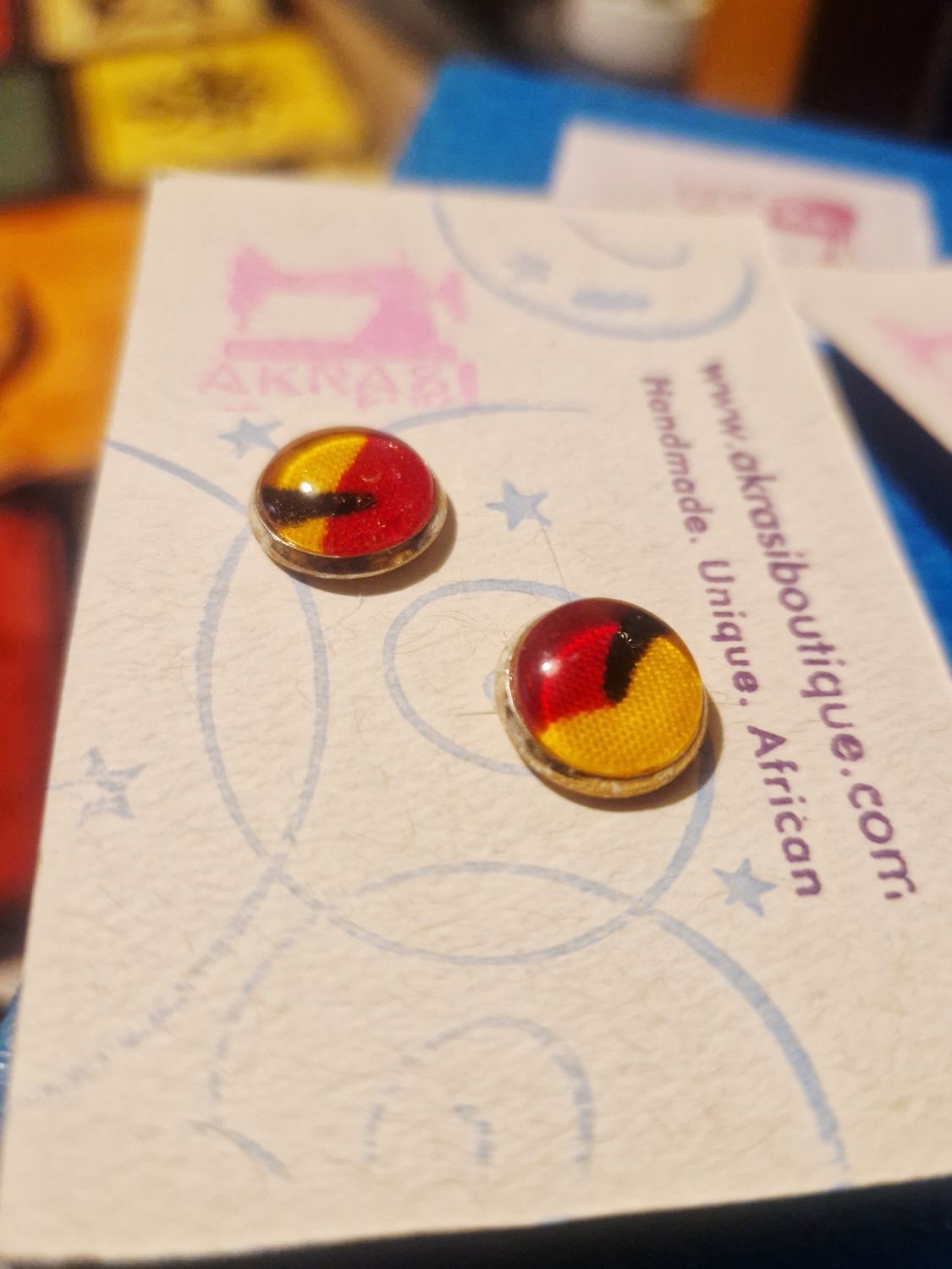 Round kente in yelloe, red and black on silver stud earrings sealed in glass Round kente in yelloe, red and black on silver stud earrings sealed in glass
