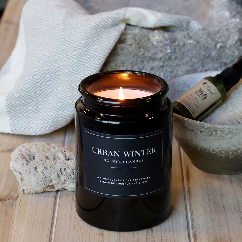 Lucon Scented Candle - Urban Winter - White Candle in Dark Glass Container. Black Label with White Writing - Shown lit
