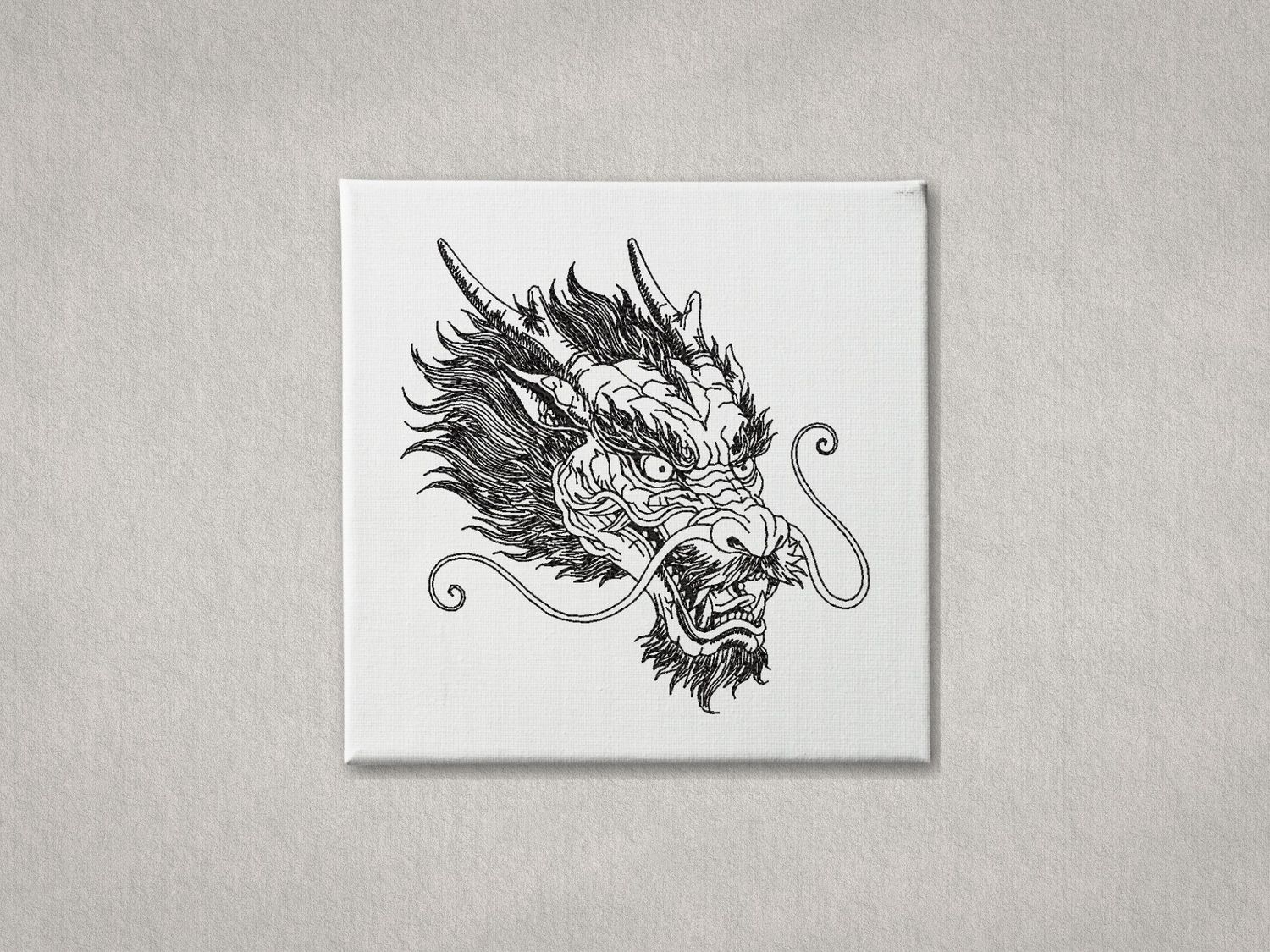 Black machine embroidery of a Chinese Dragon head on a white canvas with a grey background.