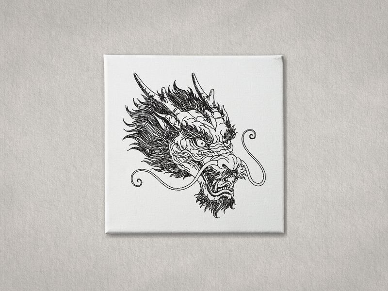 Black machine embroidery of a Chinese Dragon head on a white canvas with a grey background.