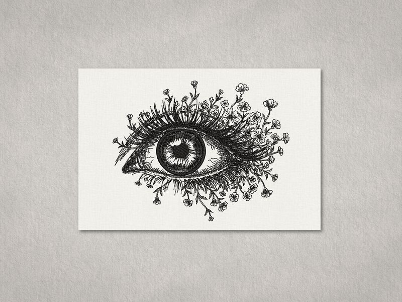 Black line embroidery of a human eye with lashes forming blooming flowers and stems on a light textured fabric background.