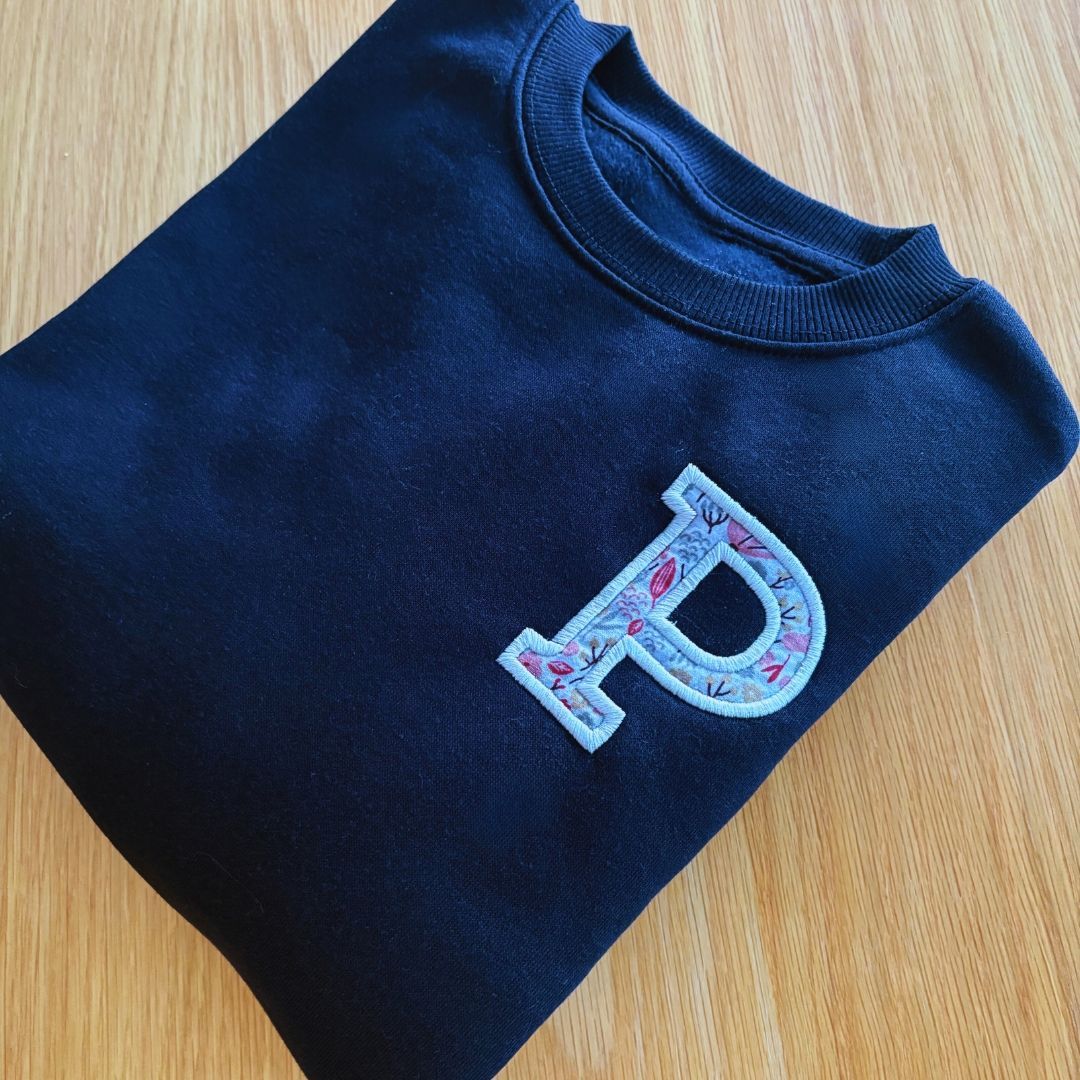 Sudadera con inicial bordada y tela floral de fondo. Sudadera con inicial bordada y tela floral de fondo.