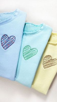 Drei Sweater mit gesticktem Herz in hellblau mit blaurotem Herz, in mint mit grünem Herz, in gelb mit goldgelben Herz.