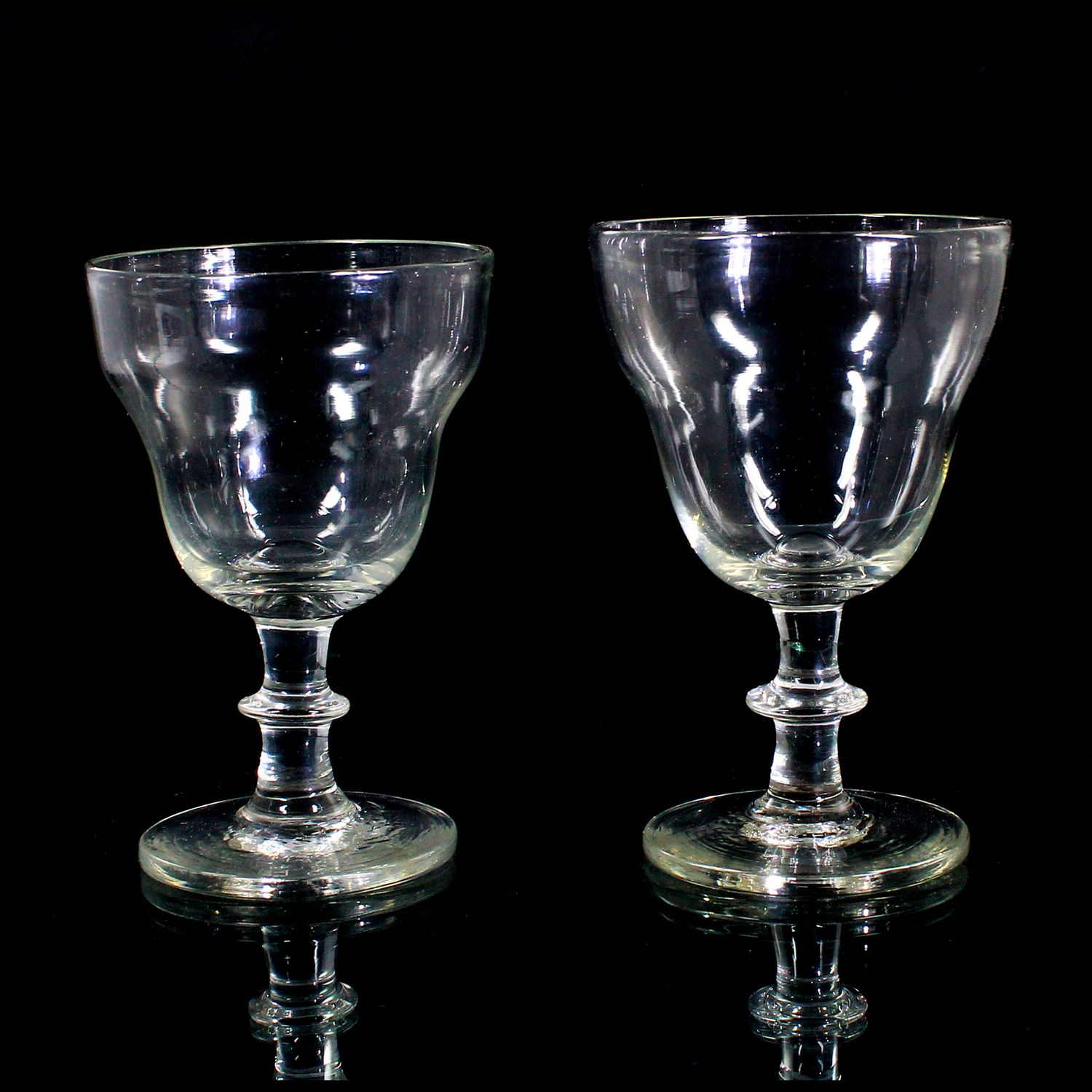 2 stemmed glasses made of colorless glass with a ball base and a pressed knop, first half of the 19th century.