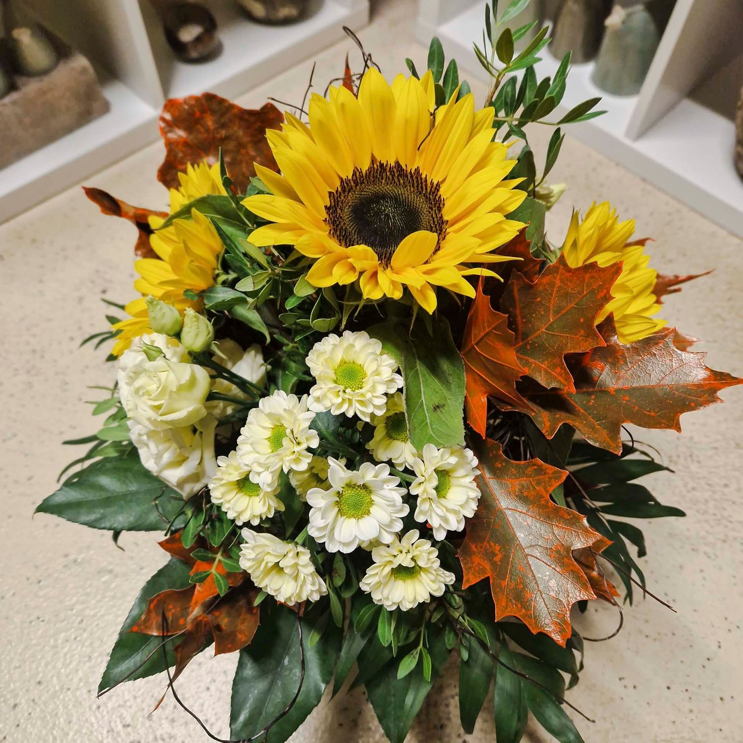 Locker gebundener Strauss mit drei Sonnenblumen, gemischten Blumen und Herbstblättern
