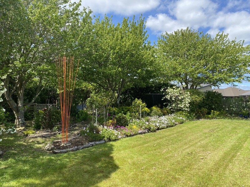 Windsticks 3m tall (without stones) 15x3m orange Windsticks (no stones) set in a garden, creating a bold and vertical architectural sculptural display