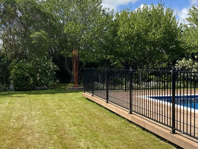 15x3m orange Windsticks (no stones) set in a garden with a swimming pool in the foreground creating a bold vertical sculpture