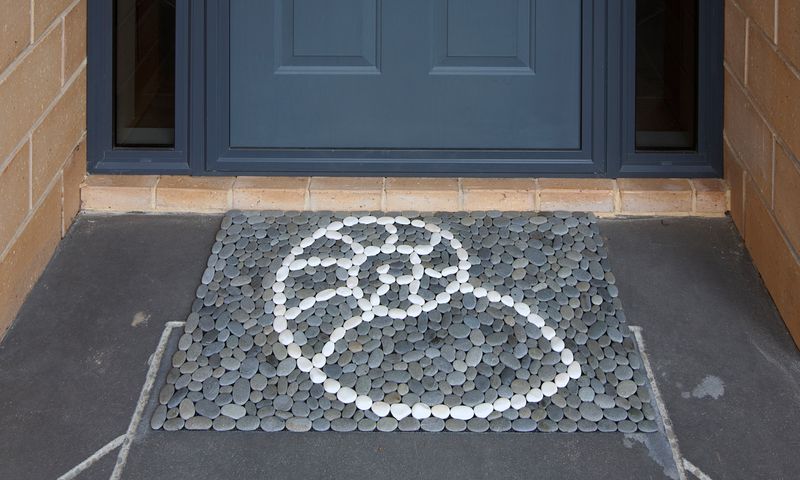 Handmade stonemat featuring a nautilus shell design in white stones surrounded by natural river stones