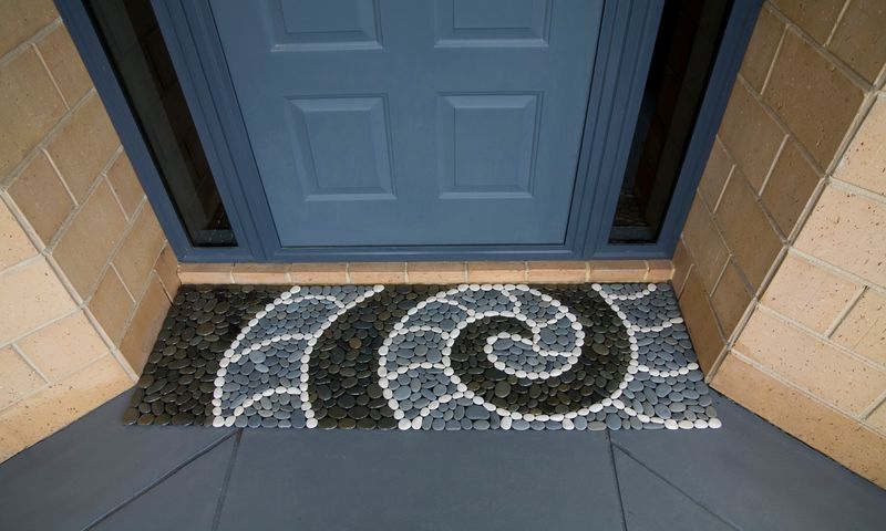 Handmade NAUTILUS KORU Stonemat combining a koru spiral and nautilus shell design with polished and natural river stones.