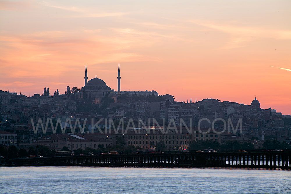 Blue Mosque in Istanbul at sunset, viewed from the bridge with the Bosphorus River in the foreground.