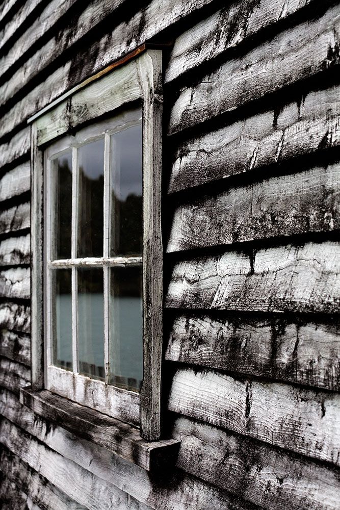 Window in an old house on Okarito wharf with black-and-white wood patina