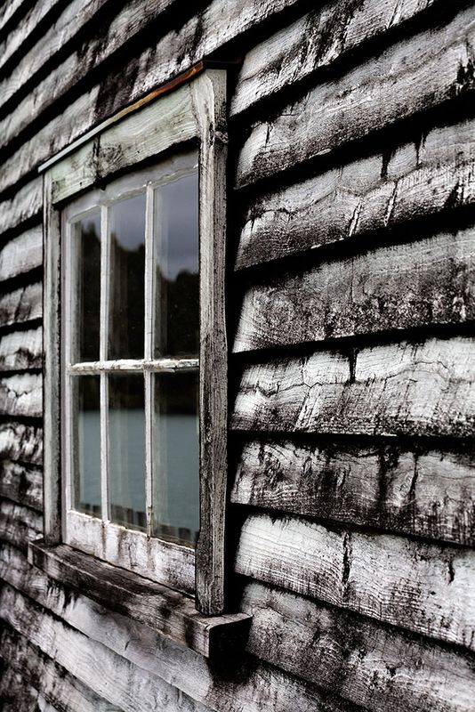 Window in an old house on Okarito wharf with black-and-white wood patina