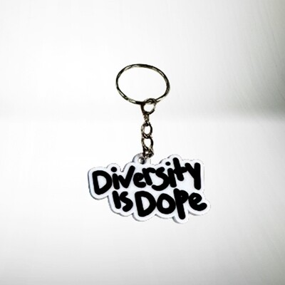 A keychain with a slogan that reads &quot;diversity is dope&quot; in stylized black and white lettering, placed on a plain white background.