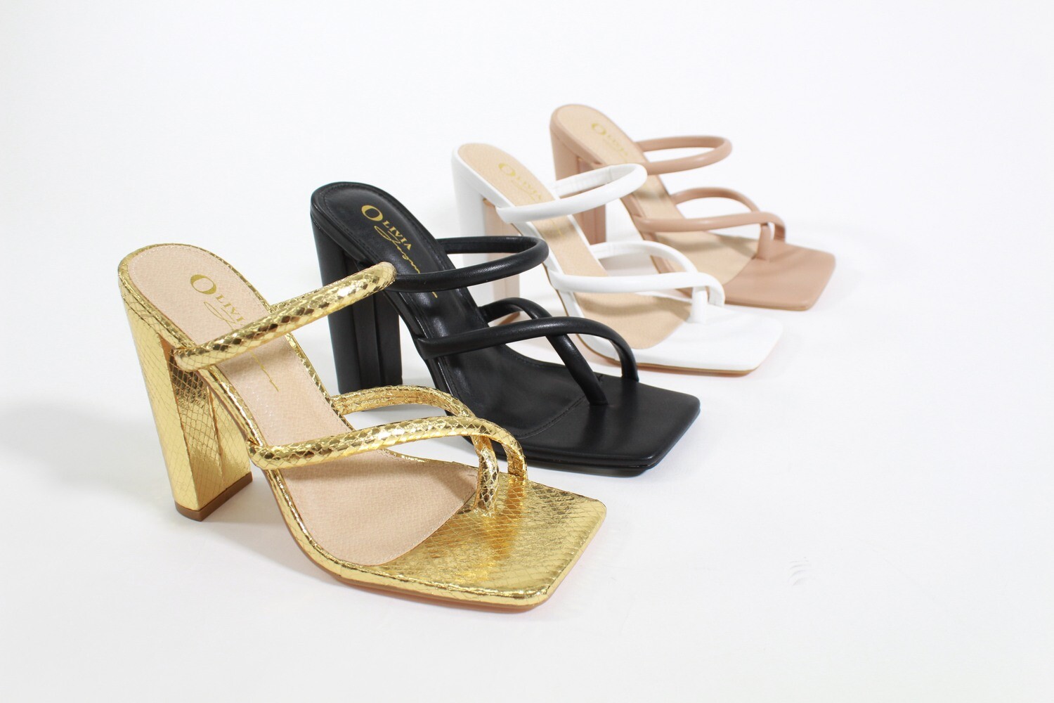 Zora high-heel sandals by Olivia in black, gold, camel, and white with sleek silhouette and ankle strap detail.