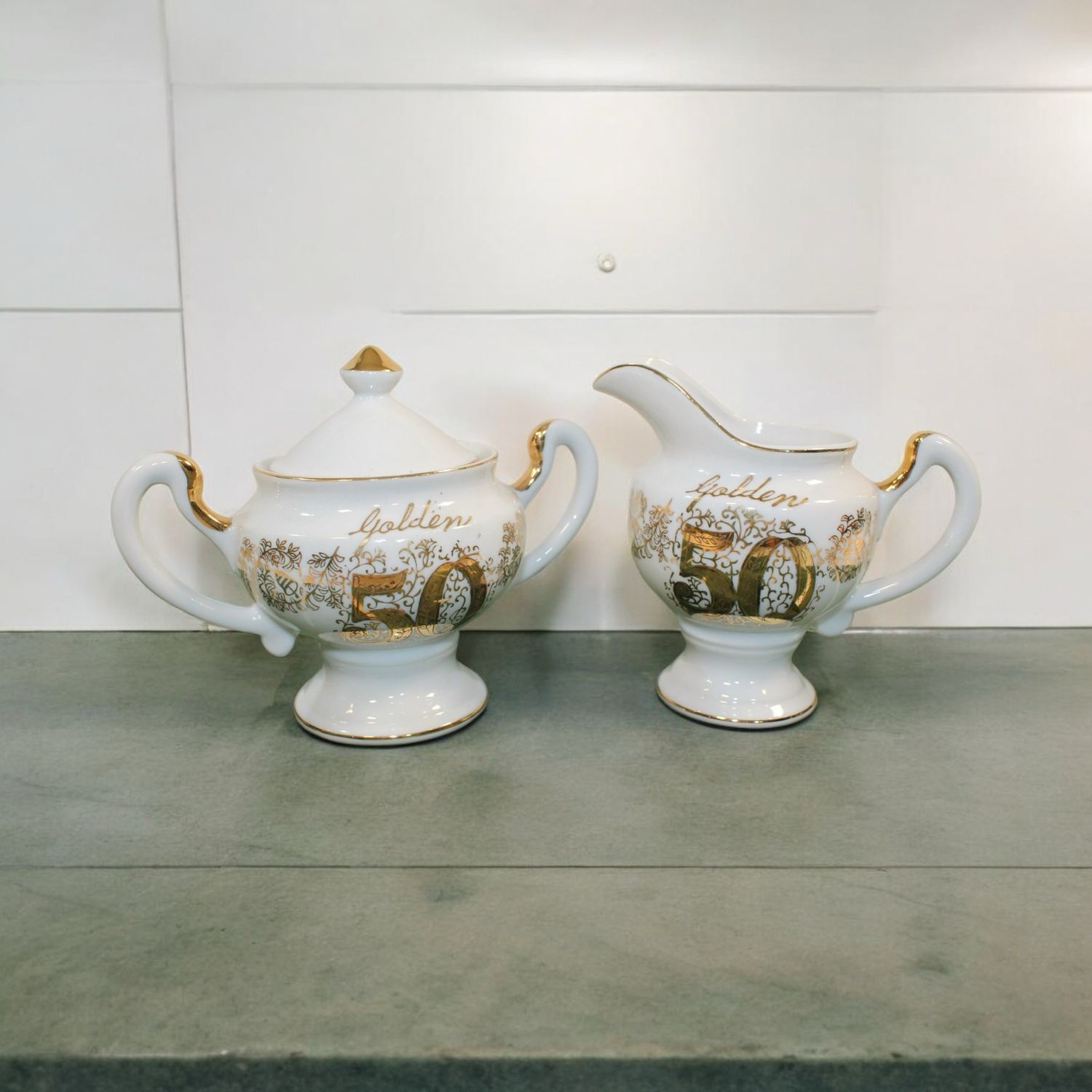 Celebrate 50 years of love and commitment with this exquisite Golden Anniversary Creamer and Sugar Bowl Set. Crafted with elegance and style, this set features a beautiful gold-tone finish that adds a touch of sophistication to any table. The sugar bowl comes with a lid.