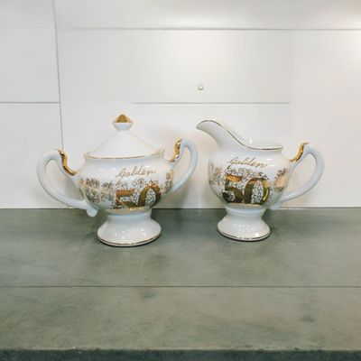 Celebrate 50 years of love and commitment with this exquisite Golden Anniversary Creamer and Sugar Bowl Set. Crafted with elegance and style, this set features a beautiful gold-tone finish that adds a touch of sophistication to any table. The sugar bowl comes with a lid.