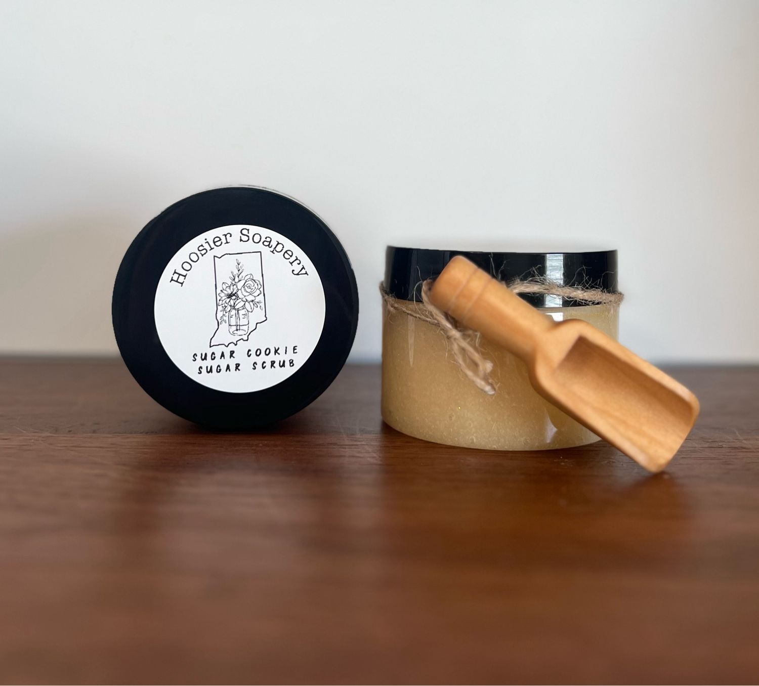 Tan Colored Sugar Scrub in plastic jars with small wooden scoop