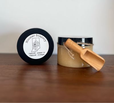 Tan Colored Sugar Scrub in plastic jars with small wooden scoop