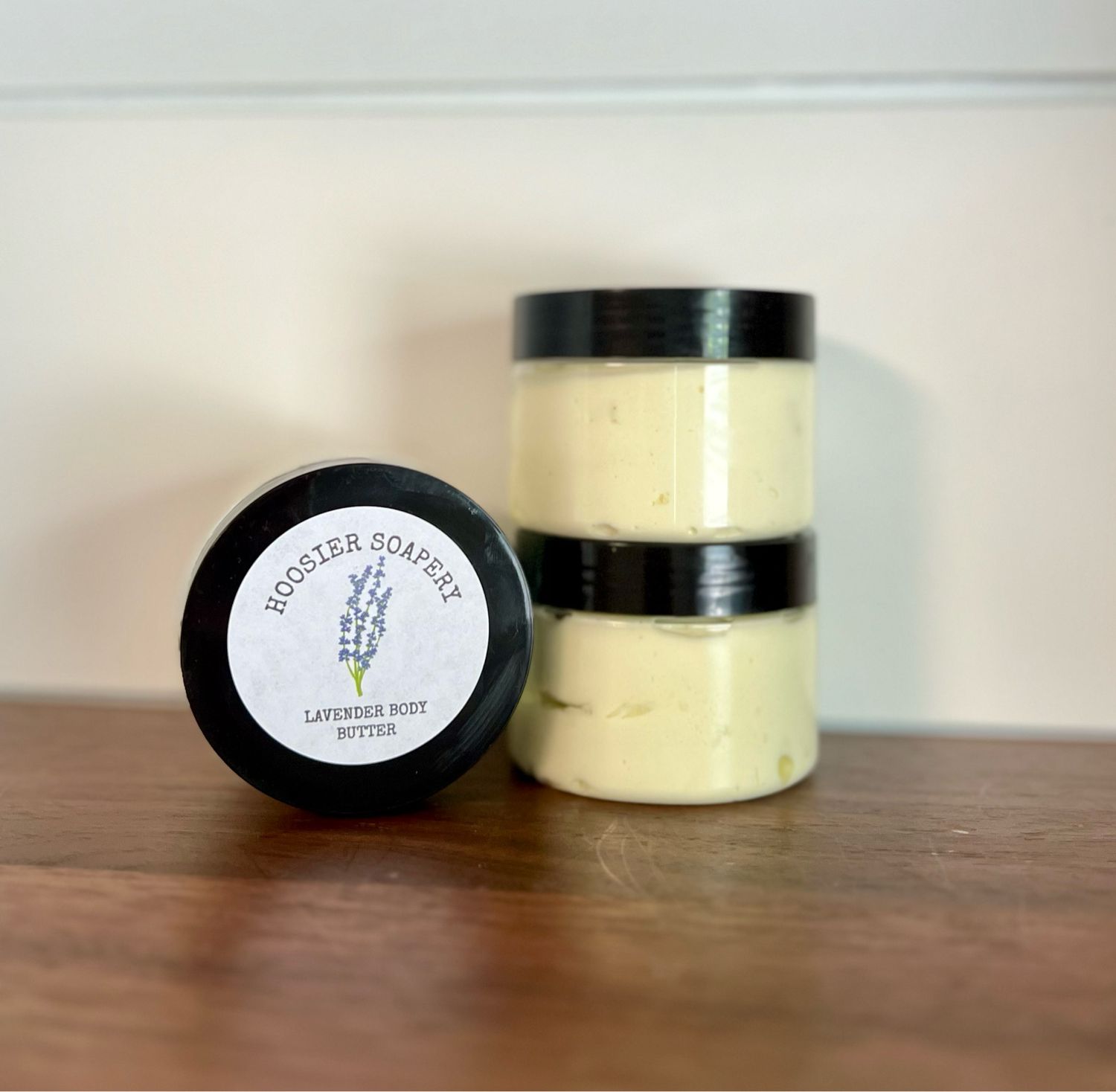 3 clear plastic jars with white lotion and black lid