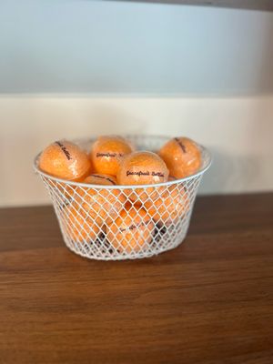 A white basket filled with orange bath bombs