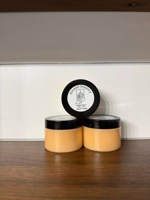 tan colored sugar scrub in a clear 4 ounce jar with black lid