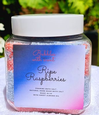Jar of &#39;Ripe Raspberries&#39; foaming bath salts by Bubbles with Scent, featuring a gradient blue to pink label and red and white bath salts, displayed in a clear glass container.