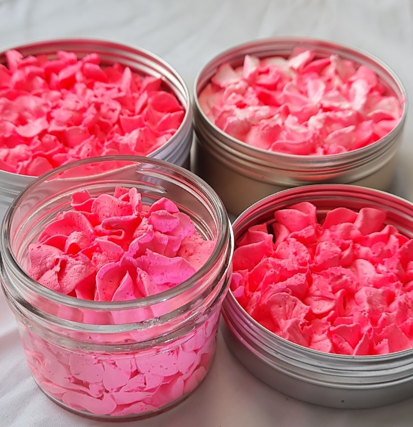 Four containers of All Smells Better in Pink whipped soap, displaying a vibrant neon pink, fluffy texture. The soap is packaged in both glass jars and metal tins