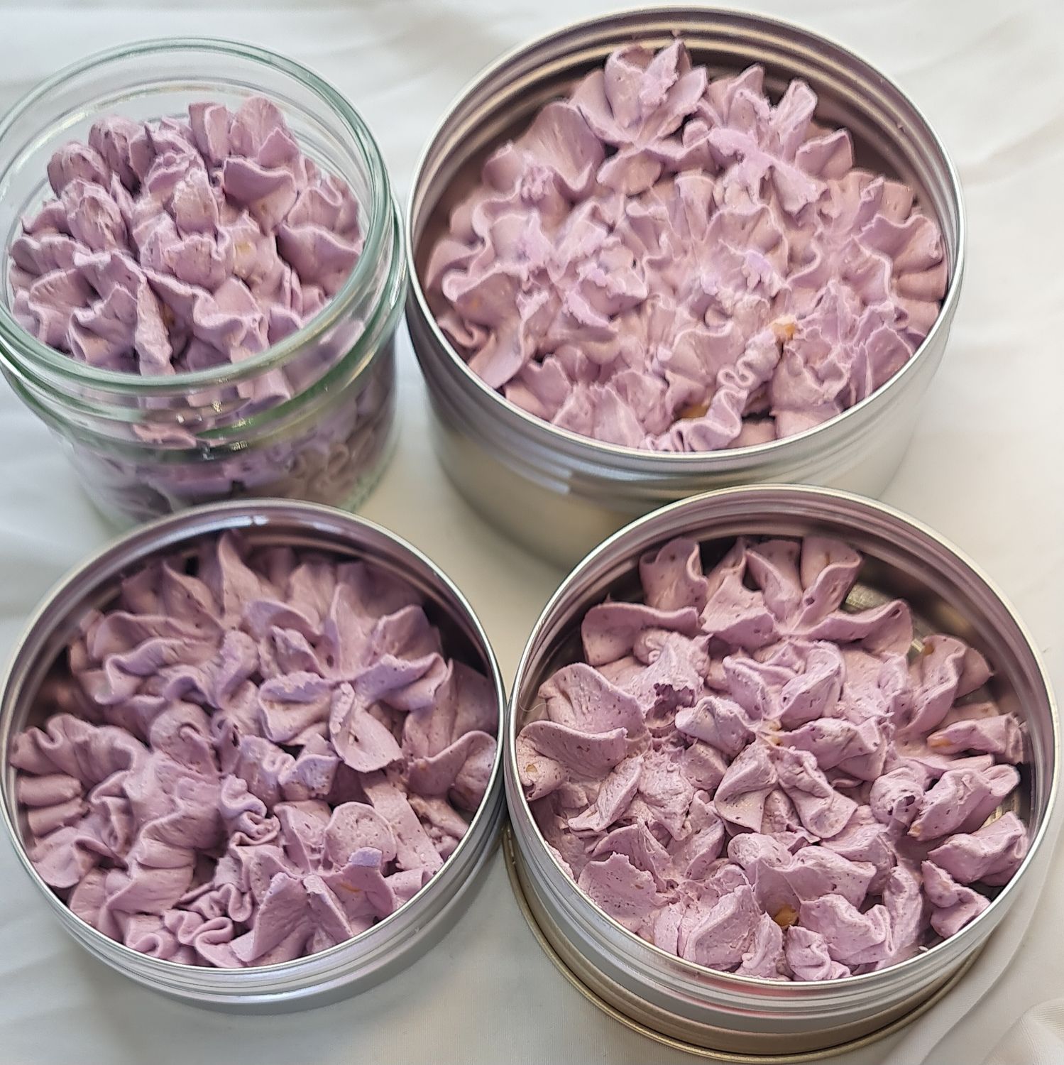 Containers of All Smells Better in Purple whipped soap, showcasing a rich purple, fluffy texture. The soap is packaged in eco-friendly glass jars and metal tins, with labels highlighting the Madam Coco-inspired fragrance.
