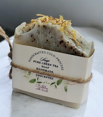 A handcrafted, cold-process soap bar labeled &quot;Pure Green Tea Soap&quot; from Bubbles with Scent. The soap is unscented, natural, and handmade, wrapped with a simple, eco-friendly paper and twine packaging, featuring dried botanicals on top