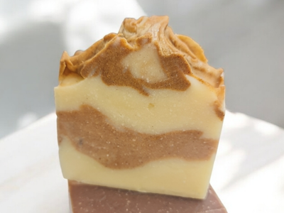 A handcrafted soap bar with a swirl pattern of creamy beige and rich brown layers, topped with a textured wave design. Made with natural ingredients, showcasing a rustic and artisanal appearance