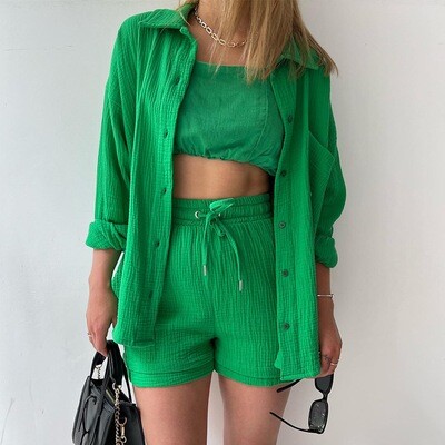 Woman in a green crinkled shirt set with high-waisted shorts, posing against a white background