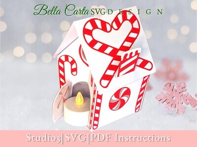 Finished 3D SVG Cricut project of a pop-up Christmas house decorated with candy canes and an LED tealight inside the door to make it glow.  This decoration is part of the Christmas Treat Village set by Bella Carta Design.