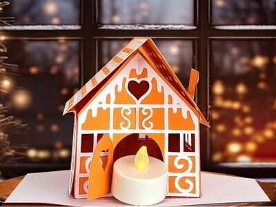 Finished 3D SVG Cricut project of a pop-up gingerbread house decorated with intricate "icing" details and an LED tealight inside the door to make it glow.  This ornament is part of the Christmas Treat Village set by Bella Carta Design.