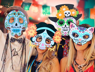 A colorful bundle of Dia de Los Muertos paper mask SVG templates seen here at a fiesta. Perfect for a Cricut project, these paper masks can be used as photo booth props or decorations at Day of the Dead celebrations. The collection includes multiple sugar skull designs, each adorned with intricate floral patterns. Featured masks include Frida Kahlo, a Caballero, La Catrina, El Catrín, a Cat Spirit Animal or Gato Alebrije. 