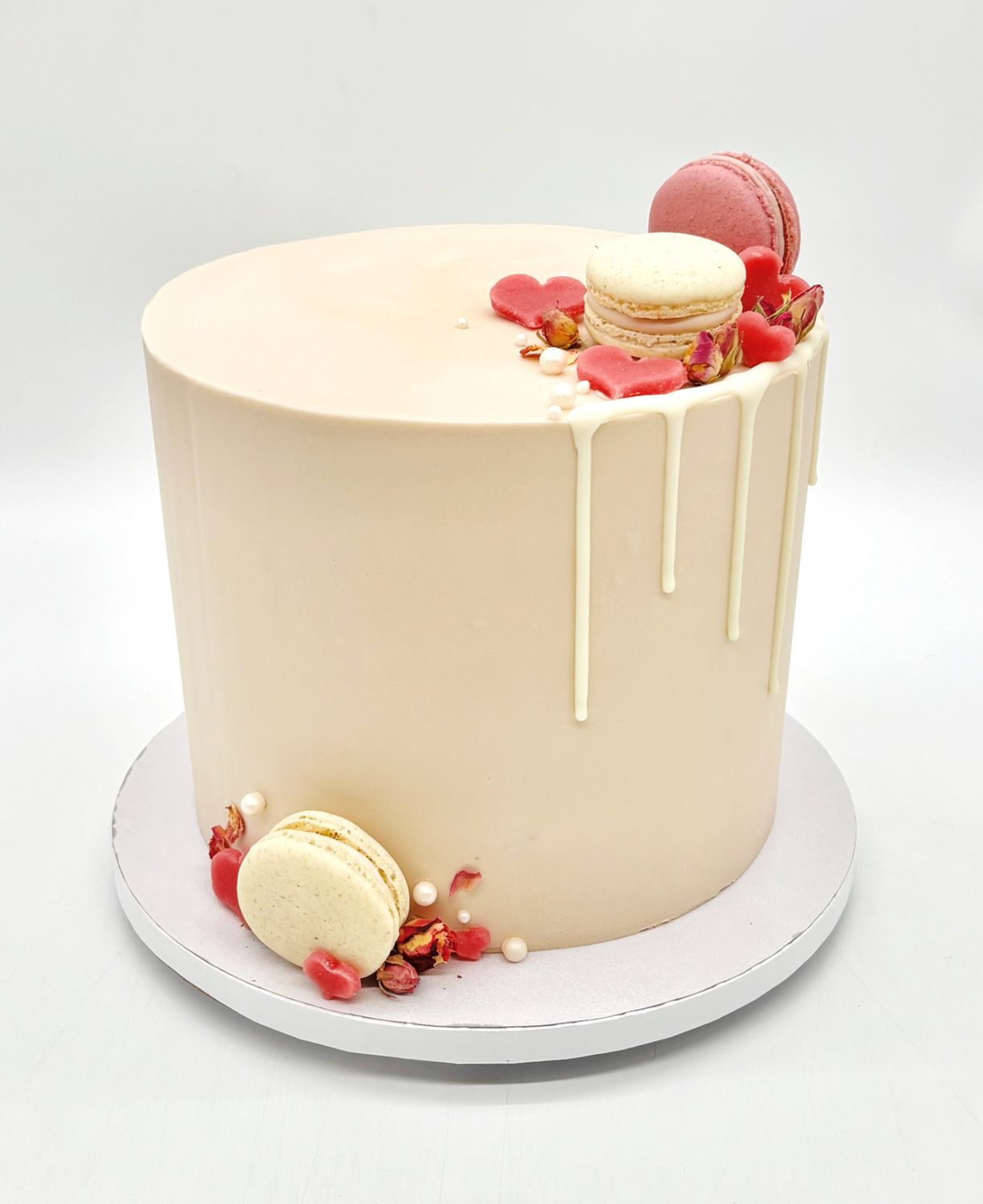 Torte mit Drip, Macarons, Herzen und essbaren Blüten