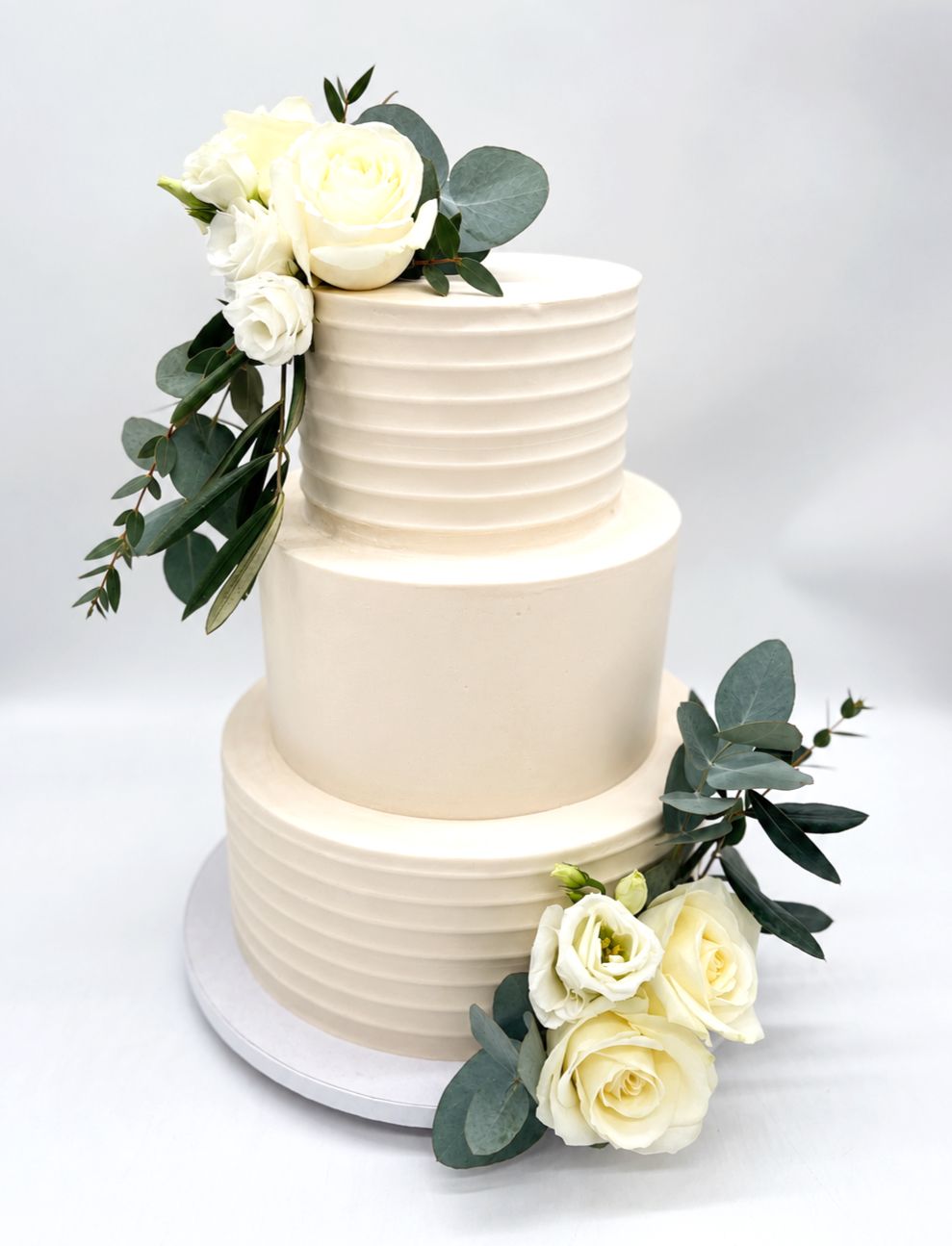 Torte mit gleichmäßiger Rillenoptik, glattem Einstrich und weißen Blumen (dreistöckig)