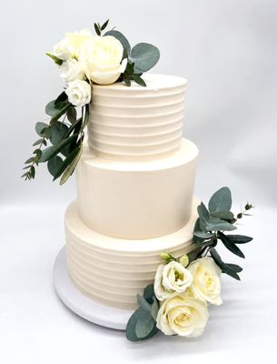 Torte mit gleichmäßiger Rillenoptik, glattem Einstrich und weißen Blumen (dreistöckig)
