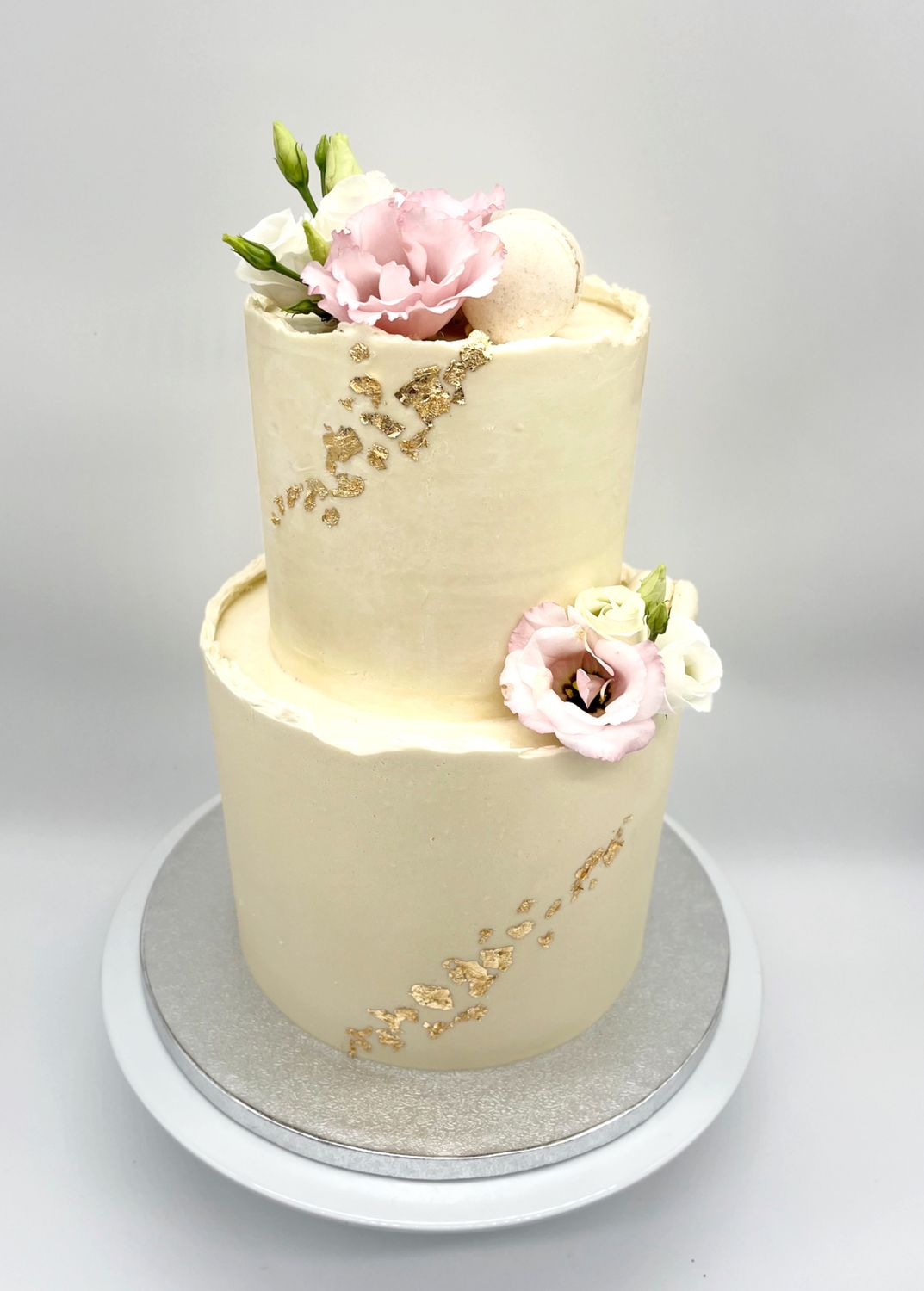 Torte mit Blattgold, Macarons und Blumen zweistöckig