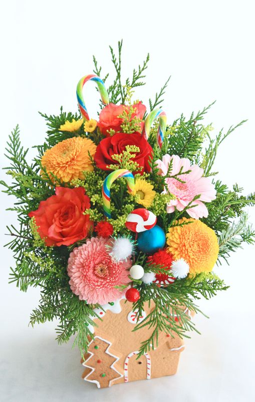 Gingerbread house with fresh flowers for christmas, with candycanes and winter greenery.