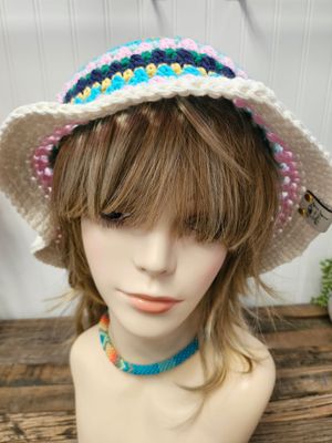 Handmade multicolored crochet bucket hat with vibrant stripes in pink, turquoise, navy, green, gold, and white, displayed on 