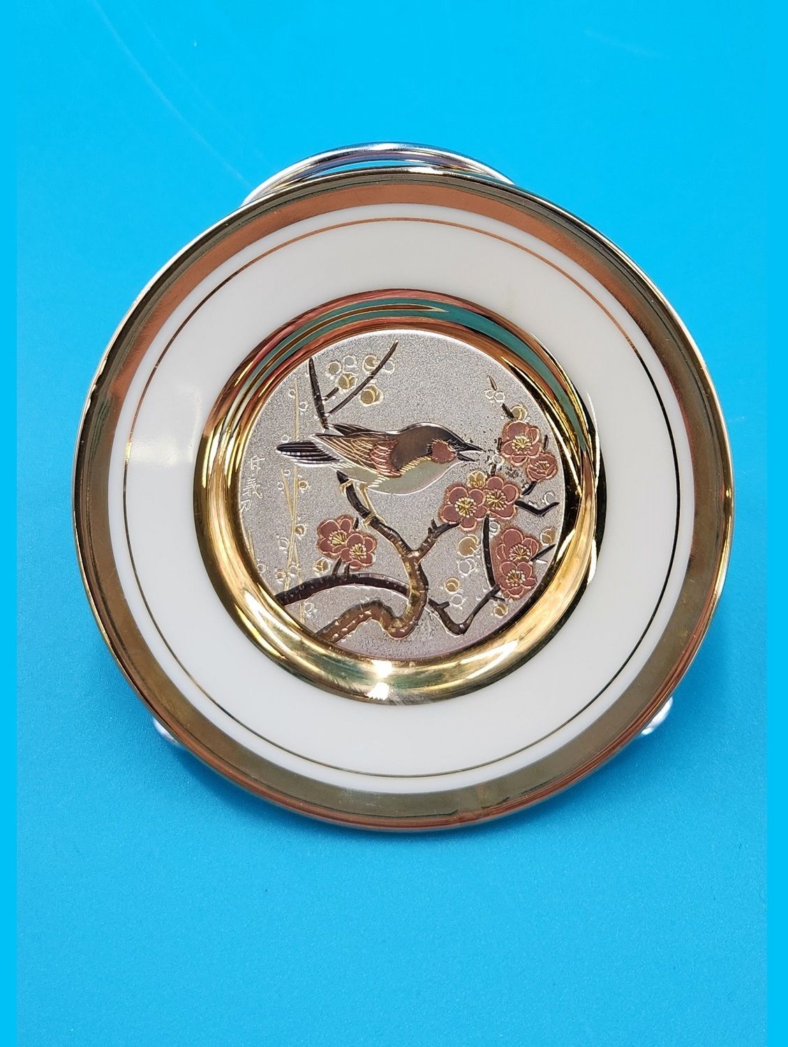 Gold rimmed plate depicting sparrow in a blossoming plum tree.