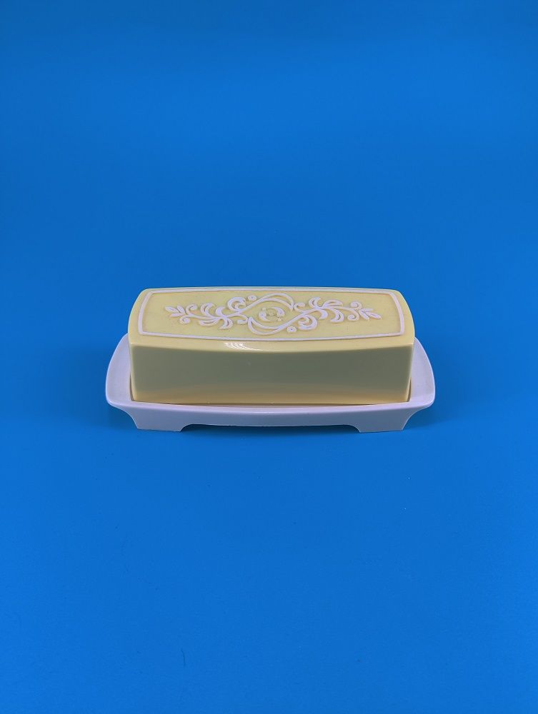  The butter dish has a yellow and white lid.