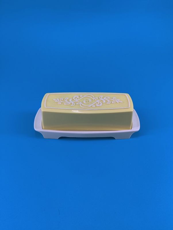  The butter dish has a yellow and white lid.