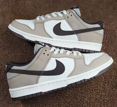 Nike Dunk low features a white leather upper with grey and brown